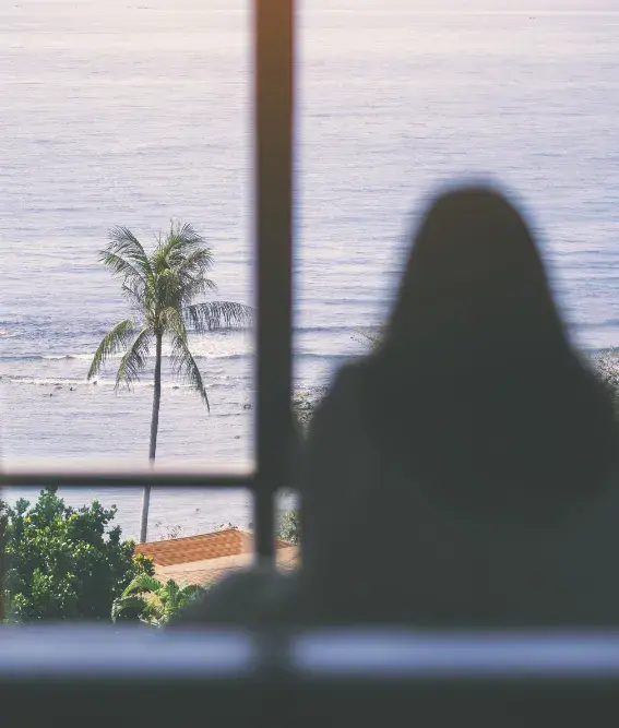 A women looking at sea from a beach home window